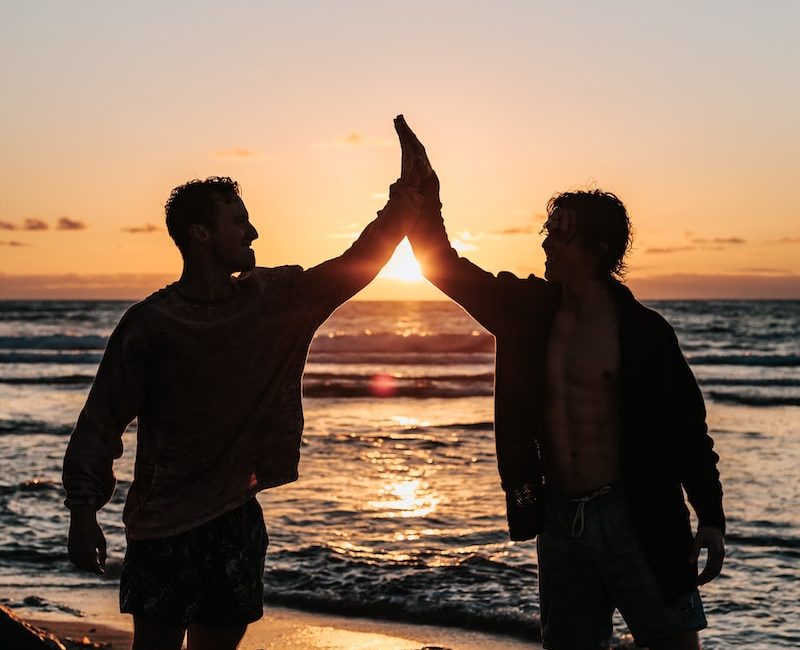 two men clapping each other on shore